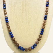 Necklace with brown and blue beads on a beige display stand