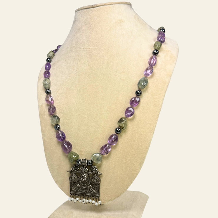 Necklace with purple and green beads on a mannequin bust against a white background