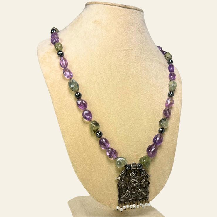 Necklace with purple and green beads on a mannequin bust against a white background