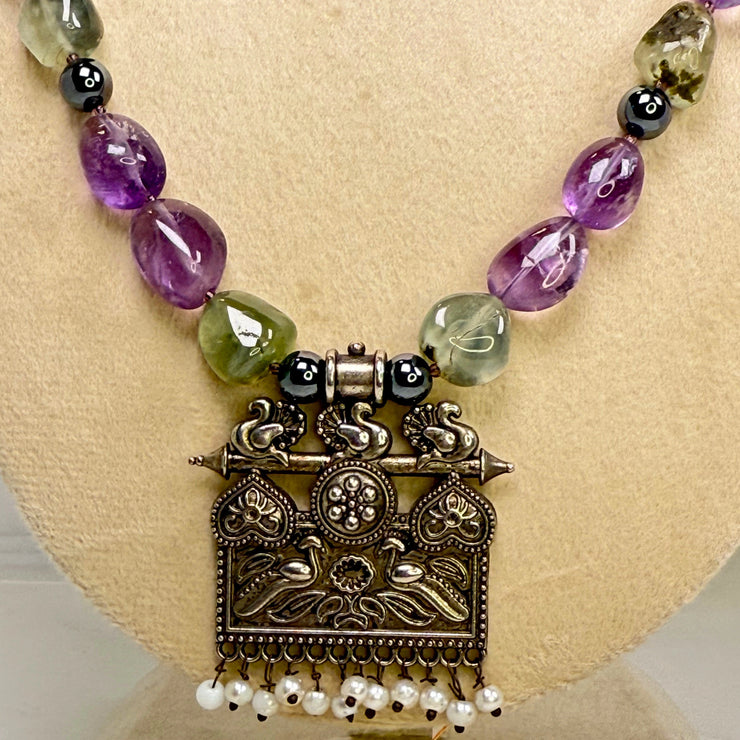 Necklace with purple and green beads on a mannequin bust against a white background