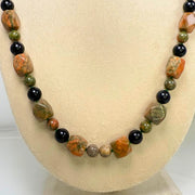 Necklace with multicolored beads on a mannequin bust against a white background