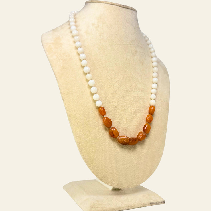 Necklace with white and amber beads on a mannequin bust against a white background