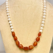 Necklace with white and brown beads on a mannequin bust.