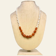 Necklace with brown and white beads on a mannequin bust against a white background