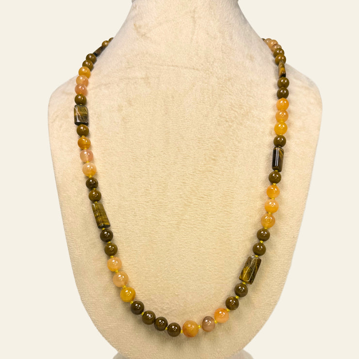 Necklace with brown and yellow beads on a mannequin bust against a white background