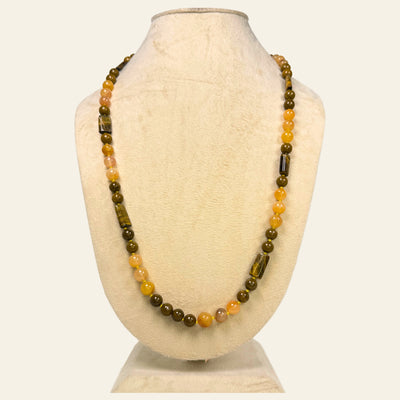 Necklace with brown and orange beads on a mannequin bust against a white background
