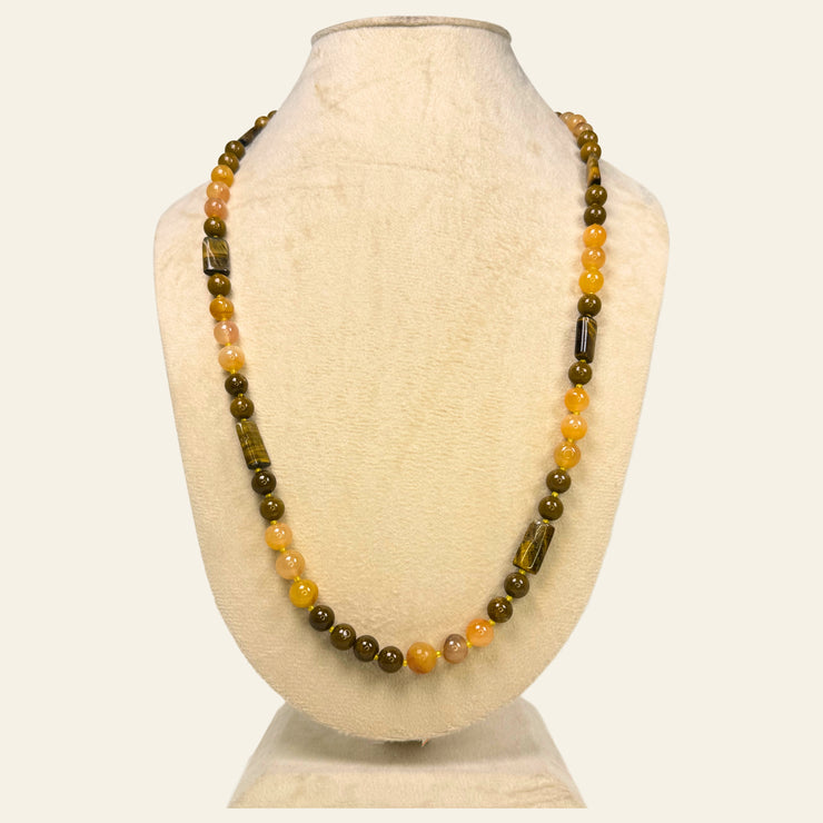 Necklace with brown and orange beads on a mannequin bust against a white background